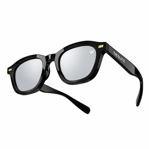 Black sunglasses with mirrored lenses, featuring a white logo on the lens and 'THE BLATIC' branding on the temple arm, shown against a plain white background.